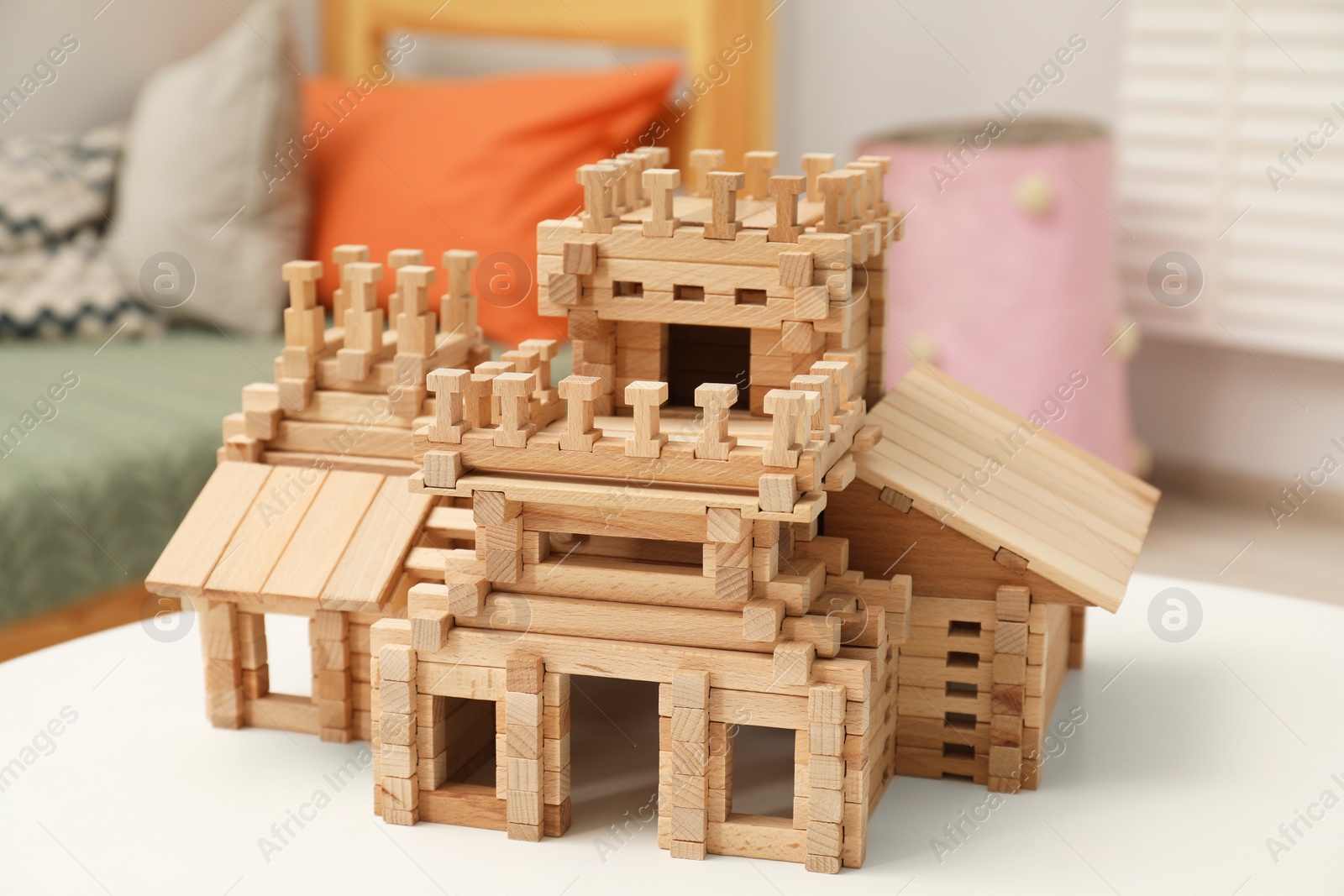 Photo of Wooden castle on white table indoors. Children's toy