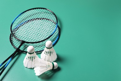 Feather badminton shuttlecocks and rackets on green background. Space for text