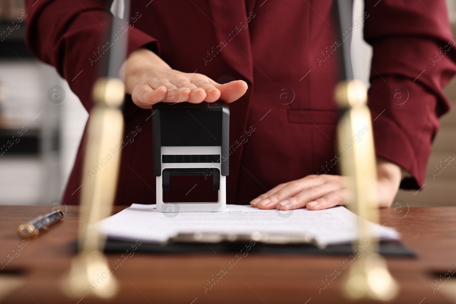 Photo of Notary stamping document at table in office, closeup