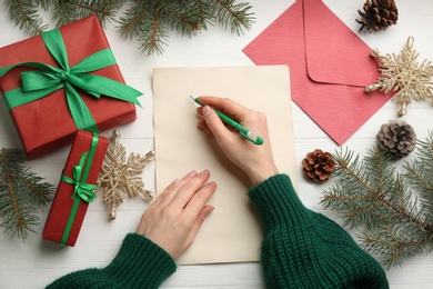 Photo of Woman writing letter to Santa at white wooden table, top view