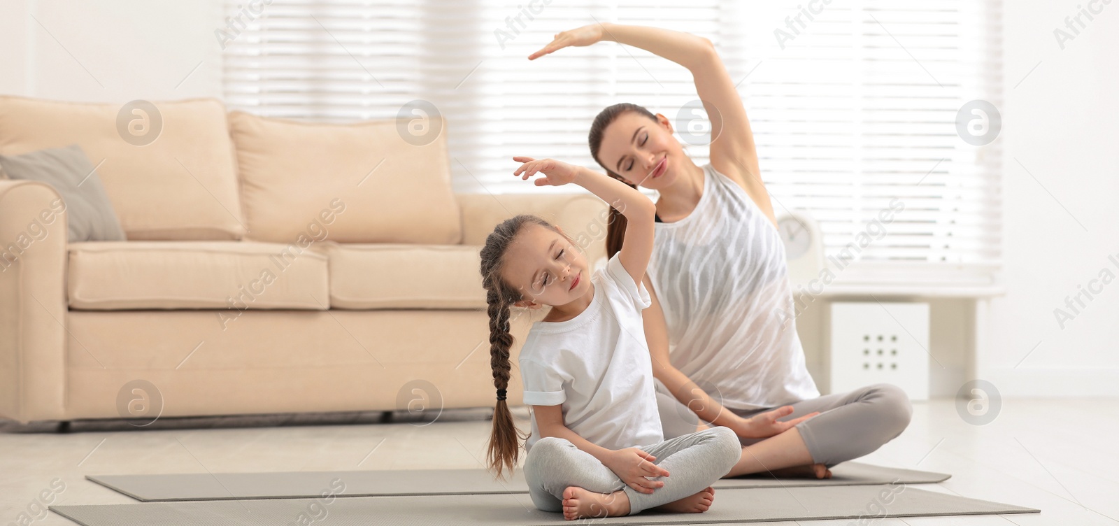 Image of Young mother with little daughter practicing yoga at home. Banner design