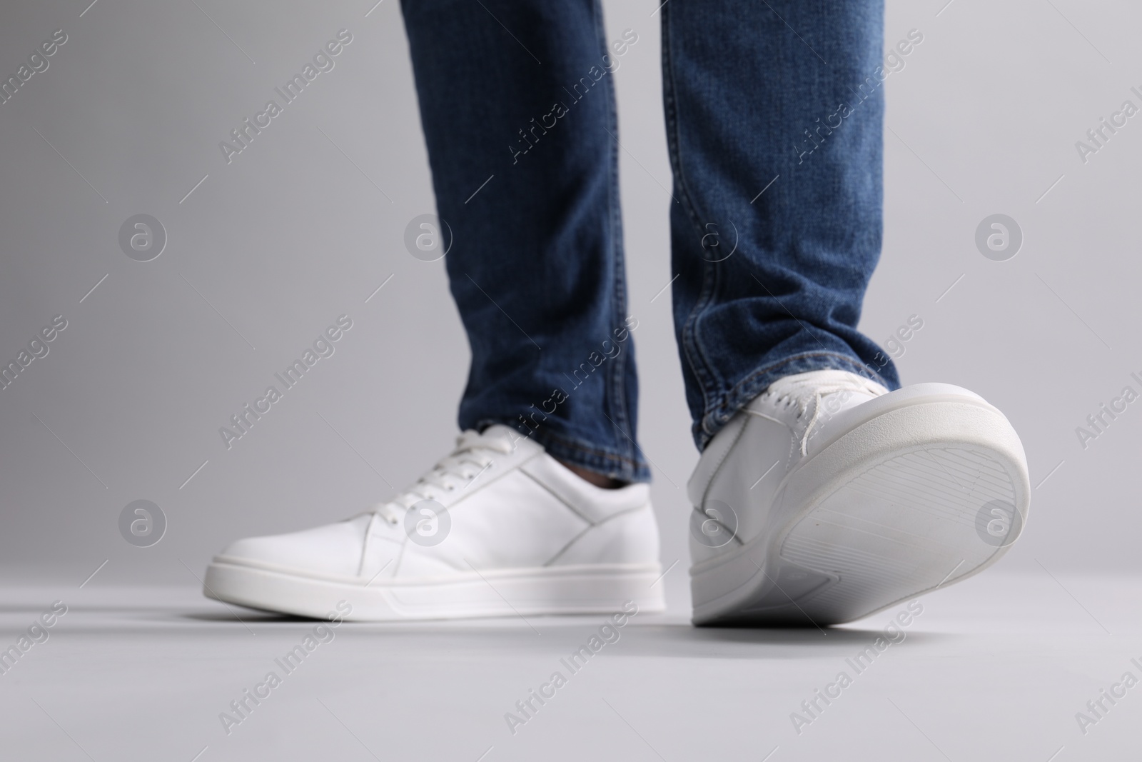 Photo of Man wearing stylish white sneakers on grey background, closeup