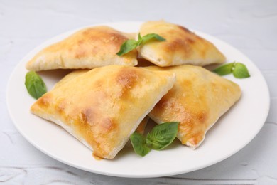 Photo of Delicious samosas and basil on white textured table, closeup