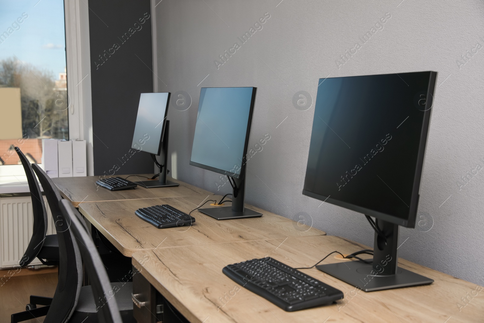 Photo of Open office interior. Modern workplaces with computers near light grey wall