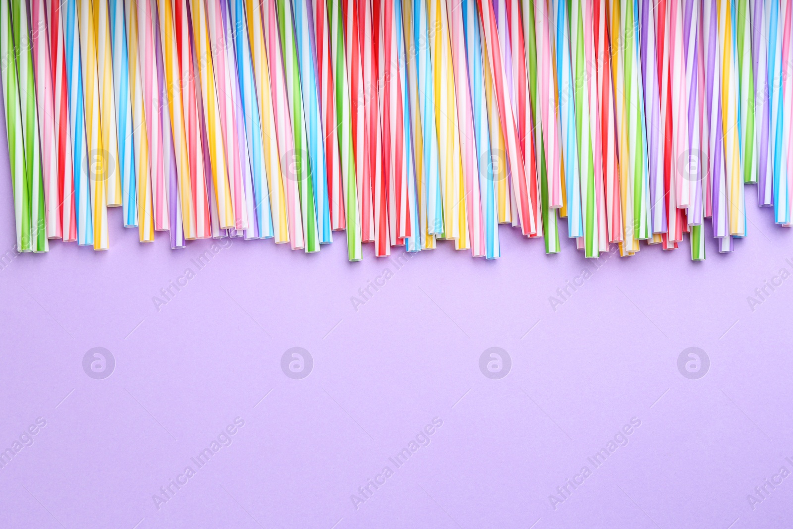 Photo of Colorful plastic drinking straws on violet background, flat lay. Space for text