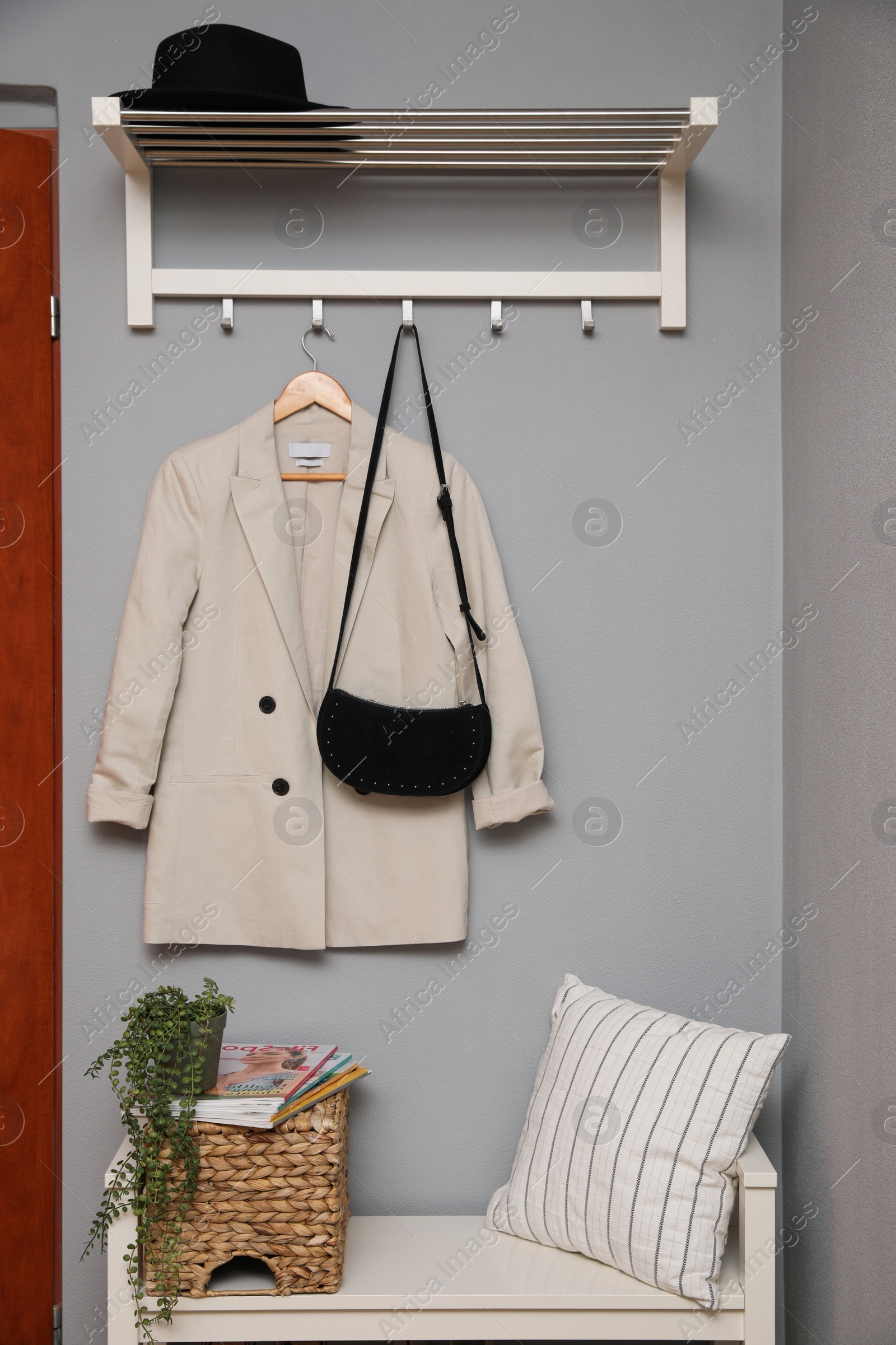 Photo of Bench and coat rack on grey wall in hallway. Interior element