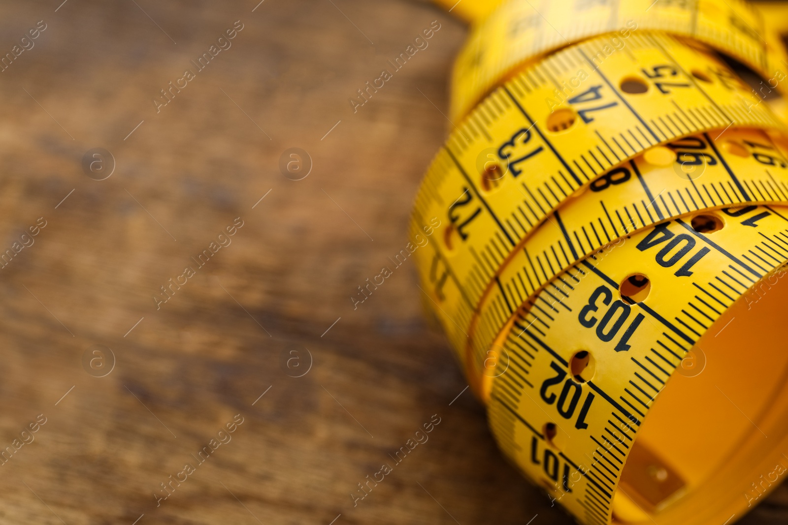 Photo of Yellow measuring tape on table, closeup. Space for text