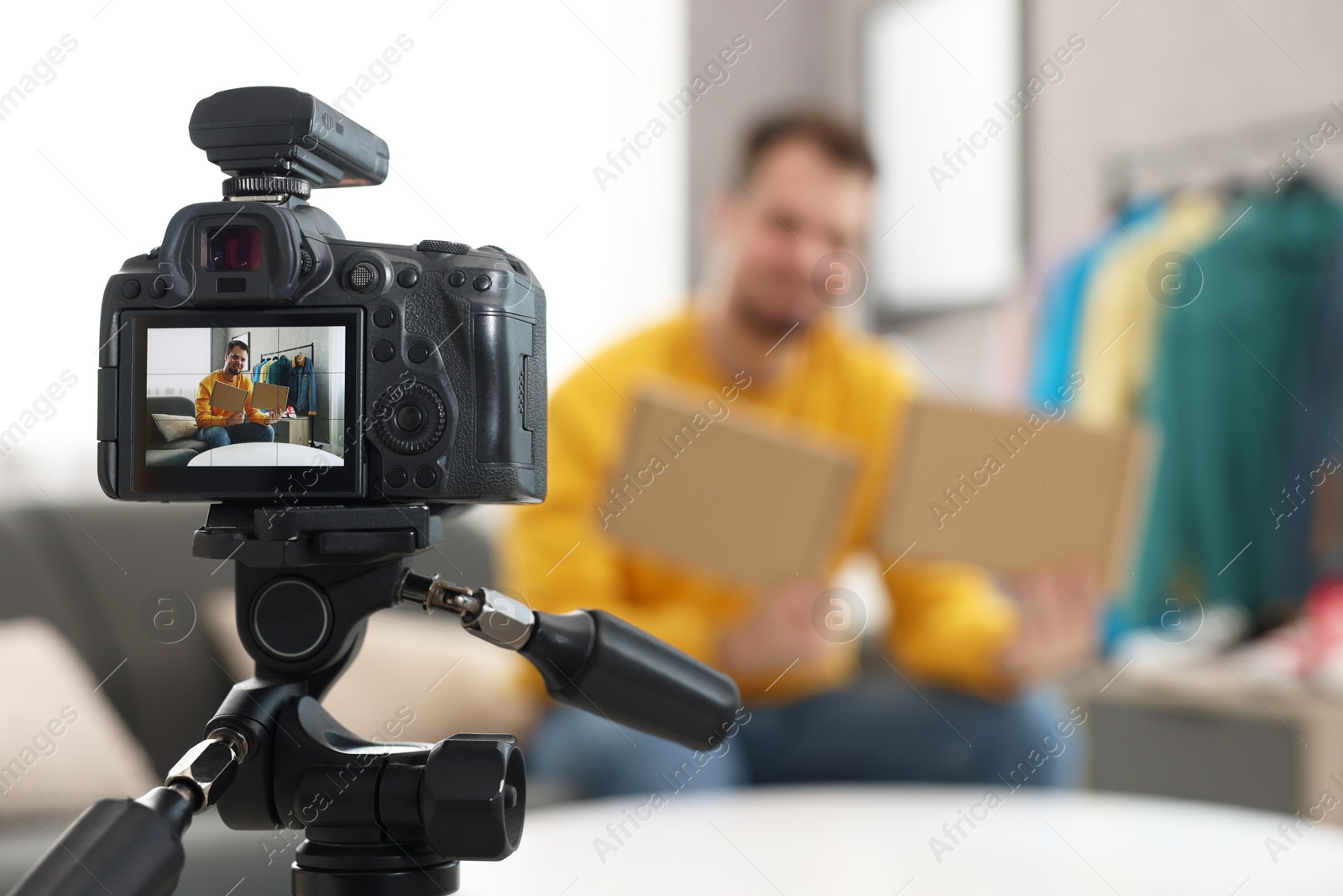 Photo of Fashion blogger with parcels recording video at home, focus on camera