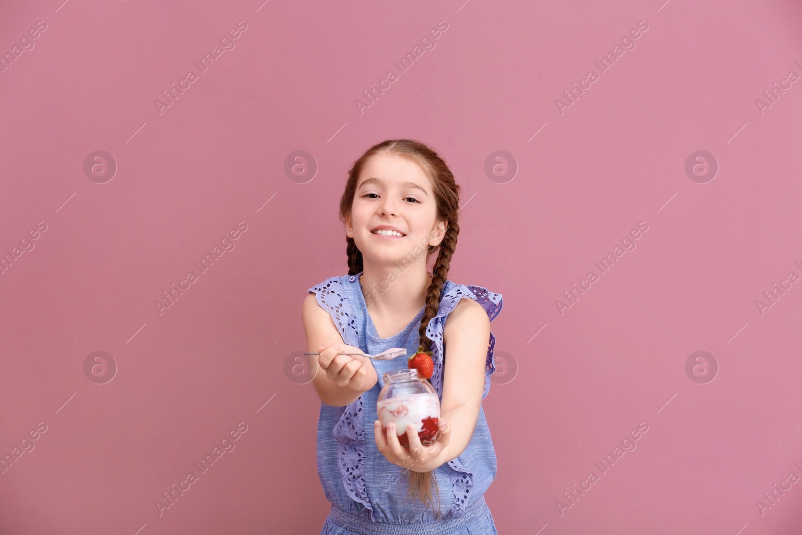 Photo of Cute girl eating tasty yogurt on color background