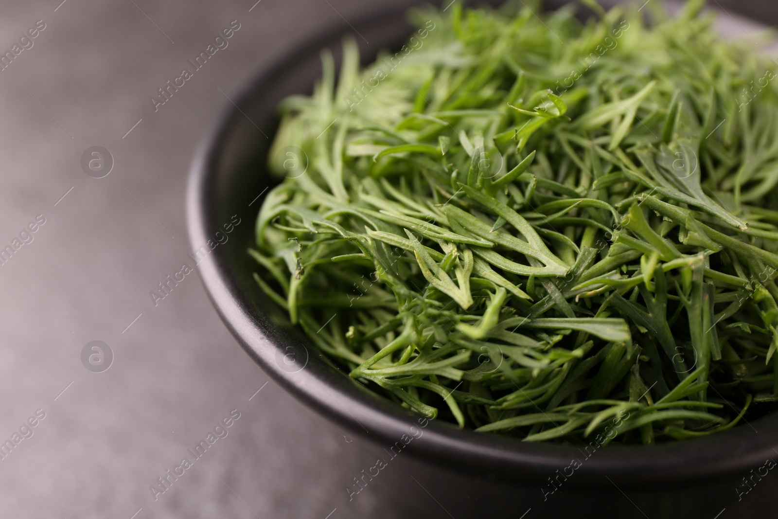 Photo of Fresh cut dill in bowl on dark table, closeup. Space for text