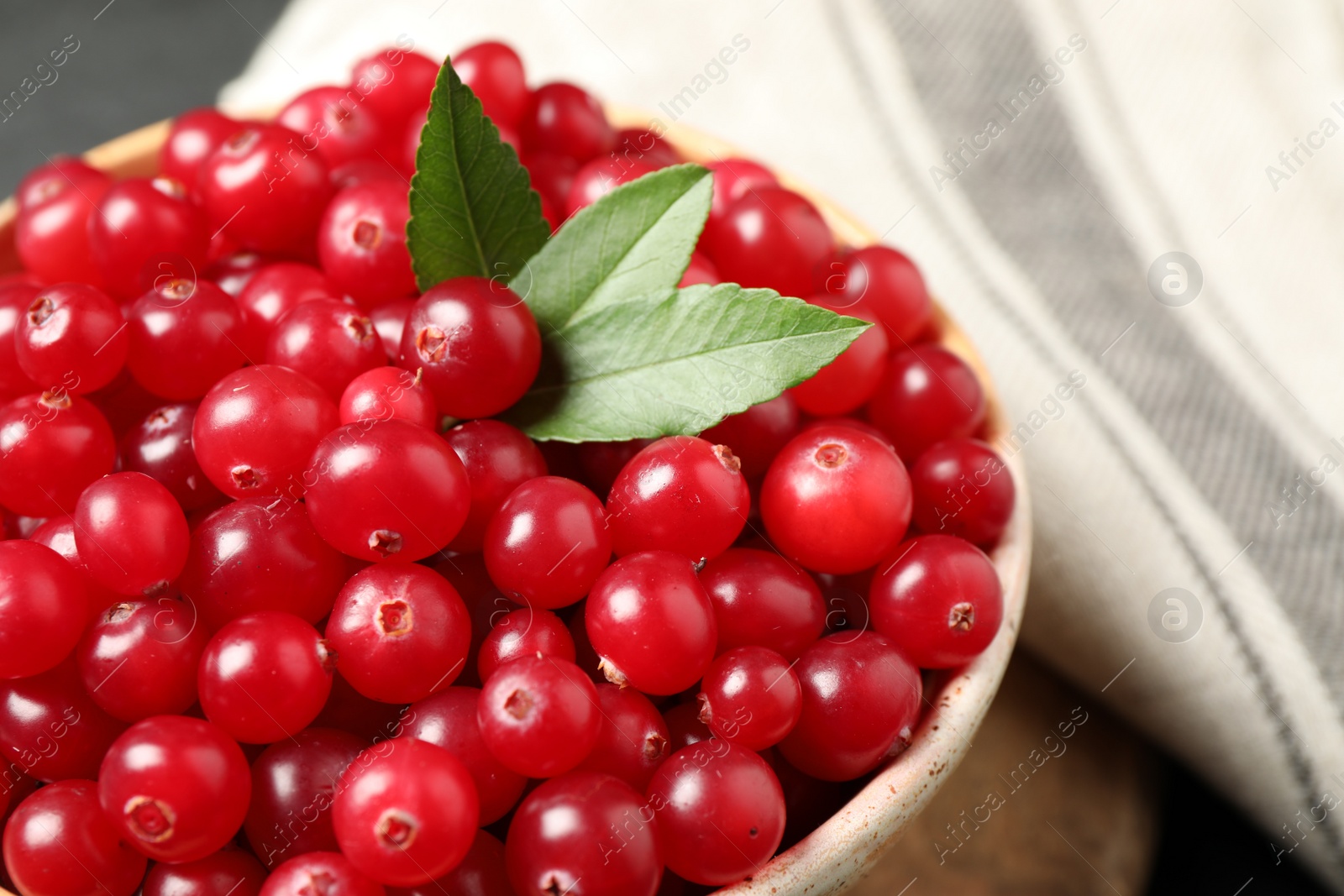 Photo of Bowl with tasty ripe cranberries on table, closeup