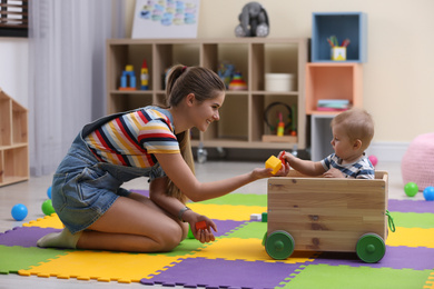 Photo of Teen nanny and cute little baby playing with toys at home