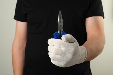 Photo of Man with needle nose pliers on light background, closeup