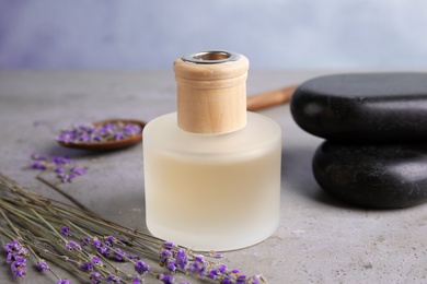 Photo of Bottle with natural herbal oil and lavender flowers on table against blurred background