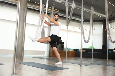 Photo of Man with hammock practicing fly yoga in studio