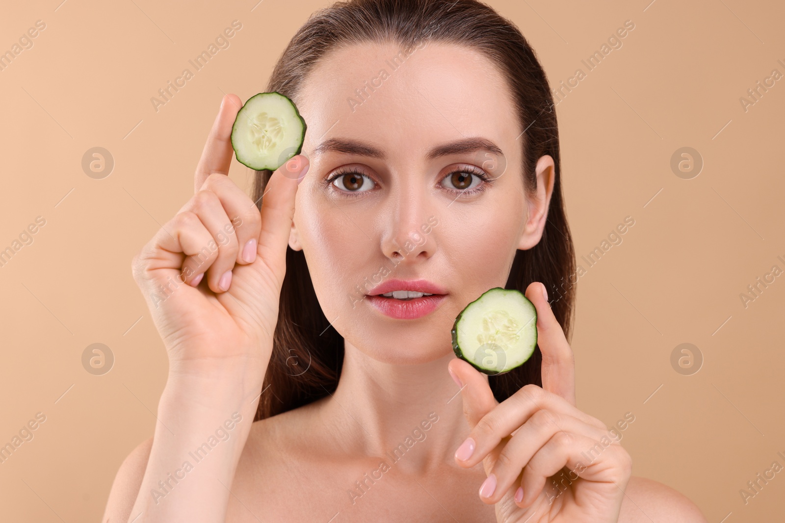 Photo of Beautiful woman with pieces of cucumber on beige background