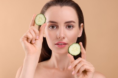 Photo of Beautiful woman with pieces of cucumber on beige background
