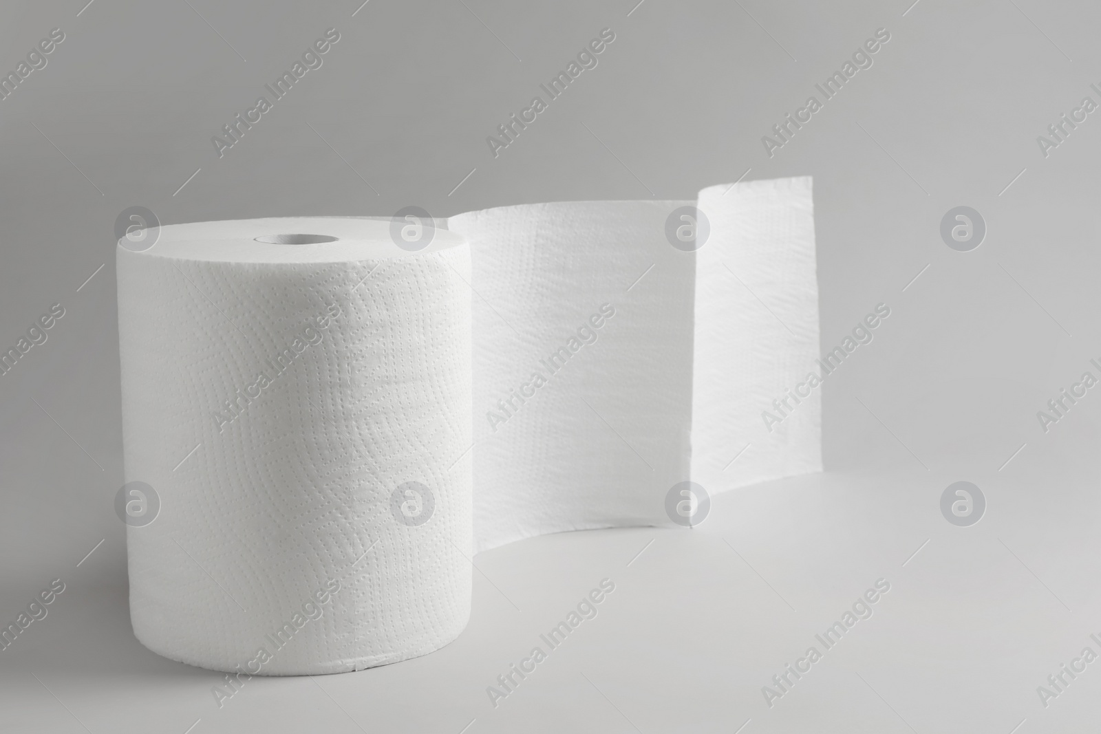 Photo of Roll of white paper towels on grey background. Space for text