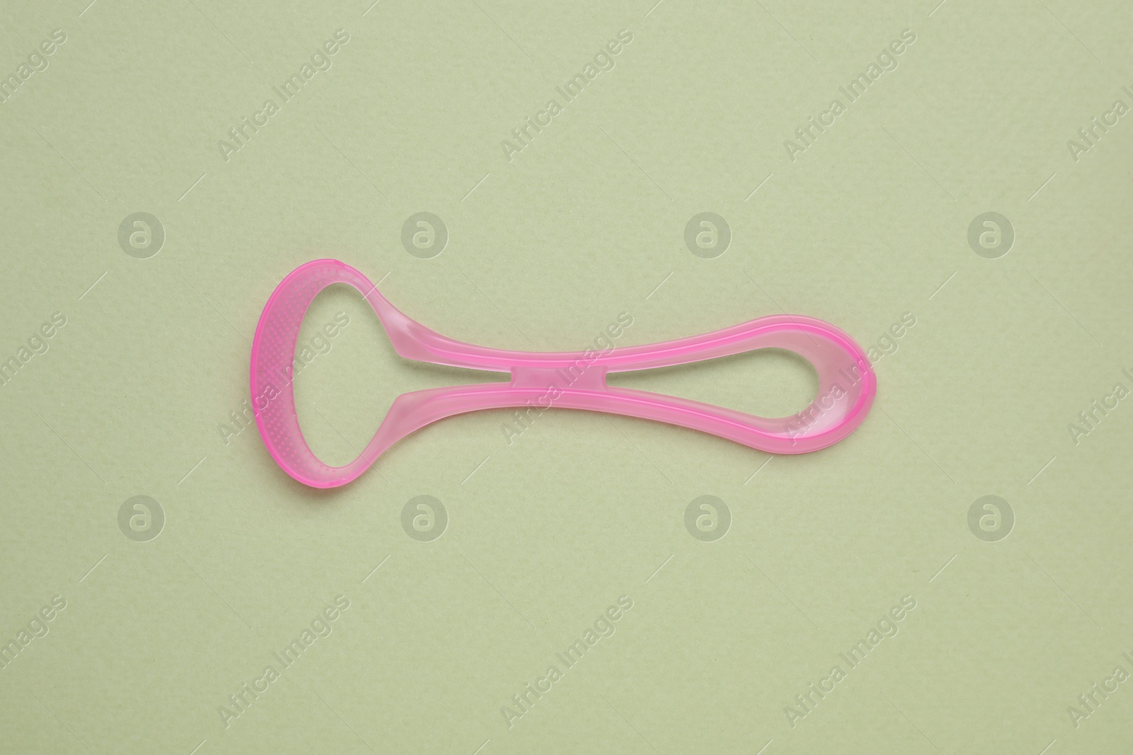 Photo of Pink tongue cleaner on olive background, top view