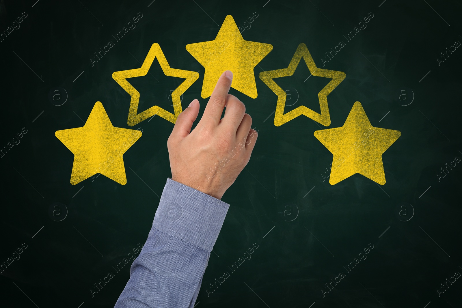 Image of Quality evaluation. Man touching golden star on green chalkboard, closeup