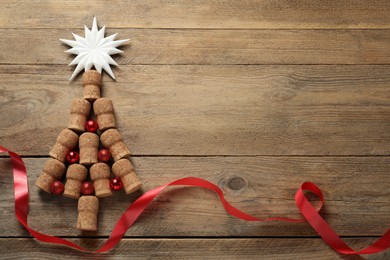 Photo of Christmas tree made of wine corks and holiday decoration on wooden table, flat lay. Space for text