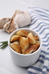 Photo of Fried garlic cloves in bowl on table, closeup