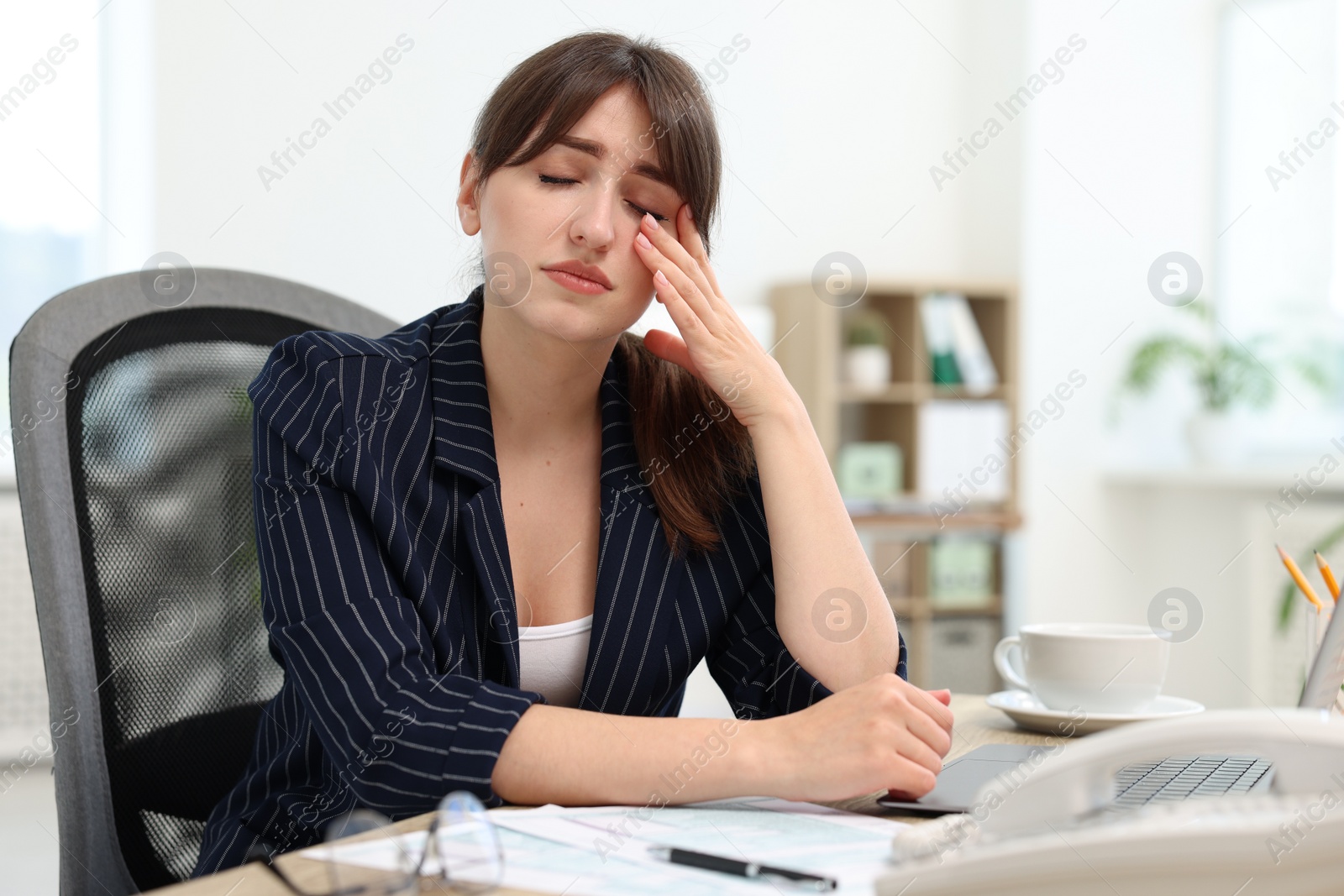 Photo of Overwhelmed woman suffering at table in office