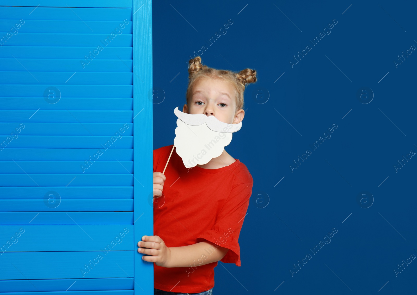 Image of Cute little girl with Santa beard prop on blue background. Christmas celebration