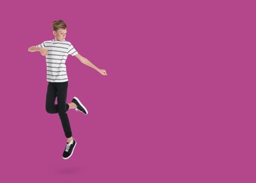 Image of Boy jumping on purple background, space for text