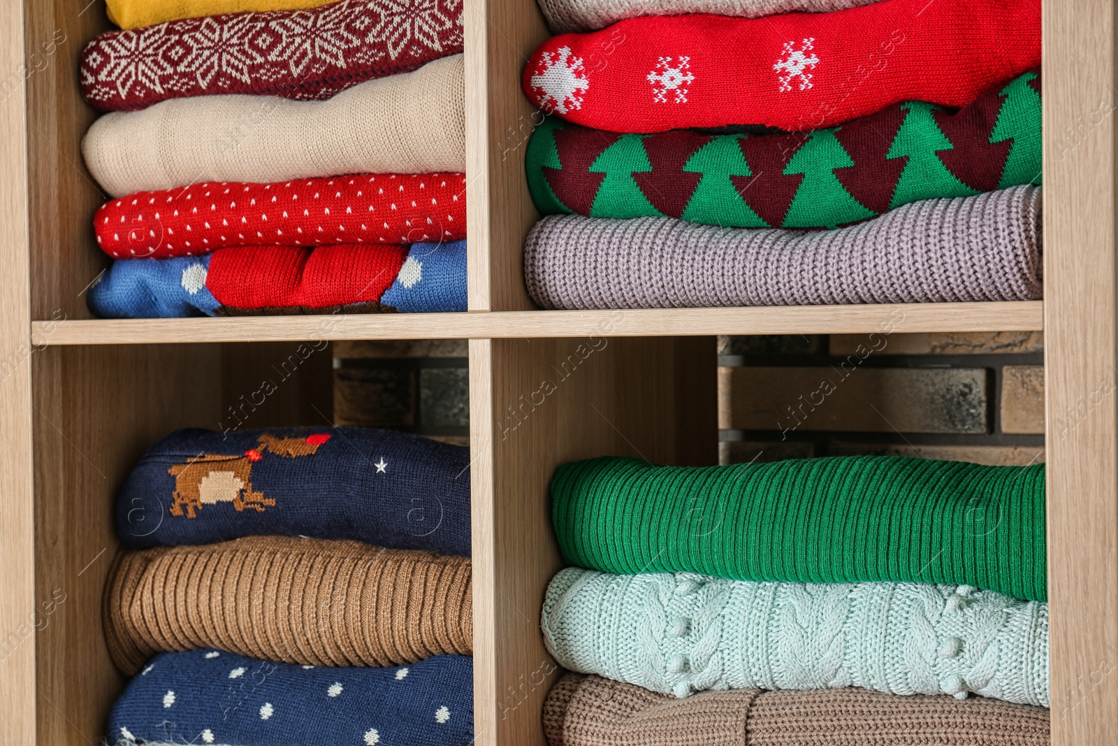 Photo of Folded winter clothes on shelves. Wardrobe storage