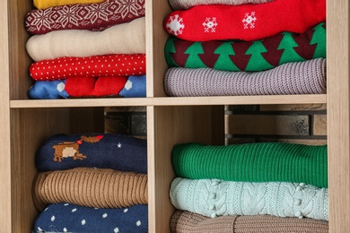 Photo of Folded winter clothes on shelves. Wardrobe storage