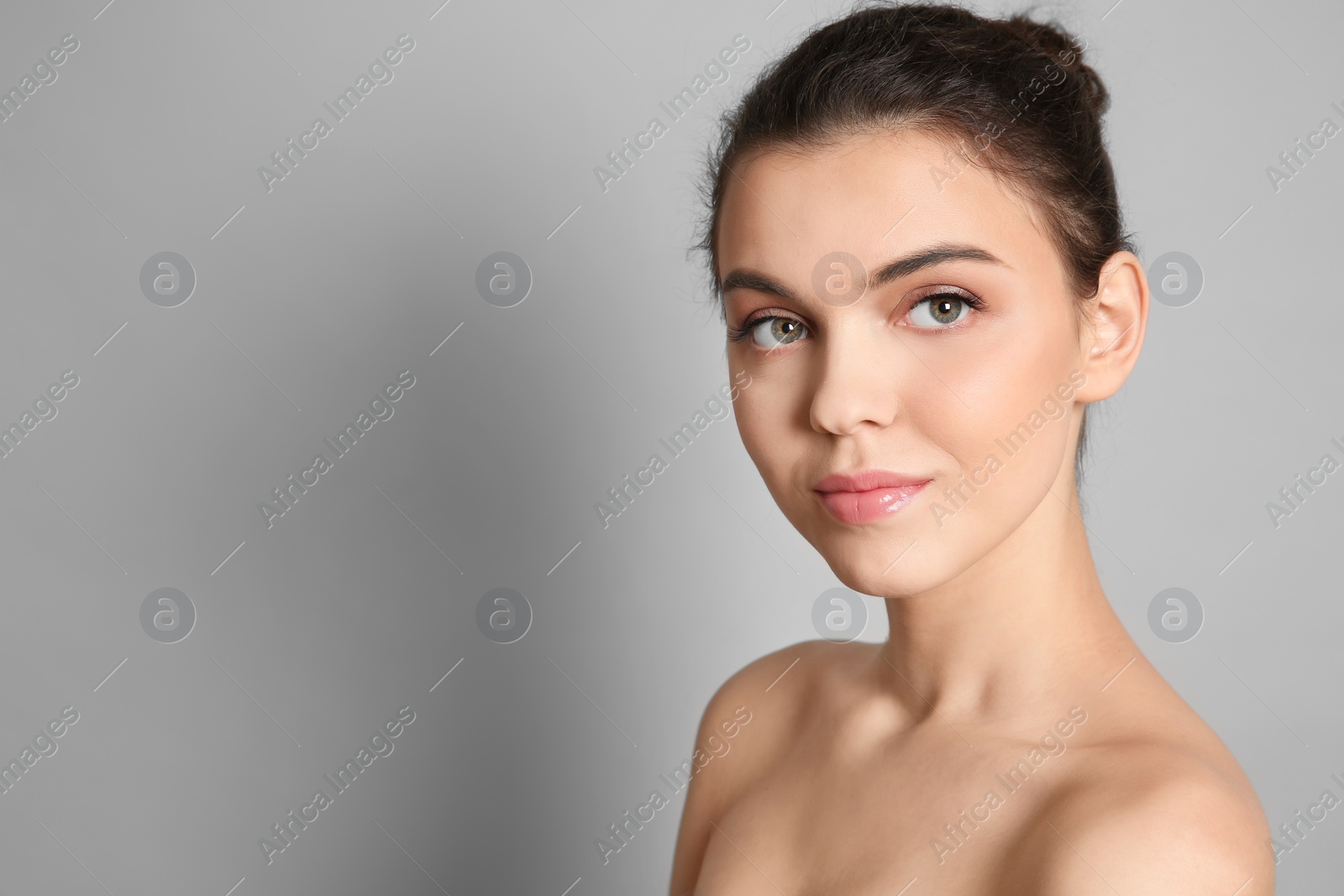 Photo of Young woman with beautiful makeup on grey background. Professional cosmetic products