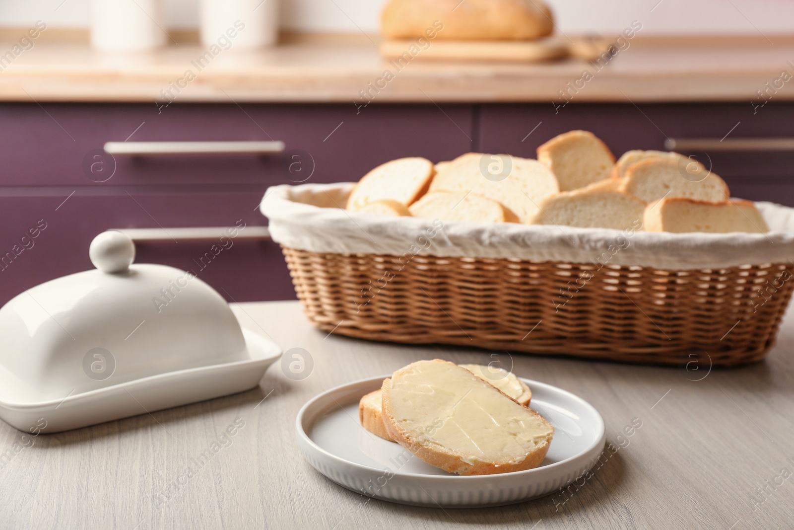 Photo of Tasty fresh bread with butter on wooden table in kitchen