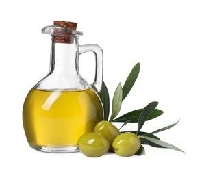 Photo of Glass jug of cooking oil, ripe olives and green leaves isolated on white