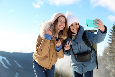 Photo of Friends taking selfie in mountains during winter vacation