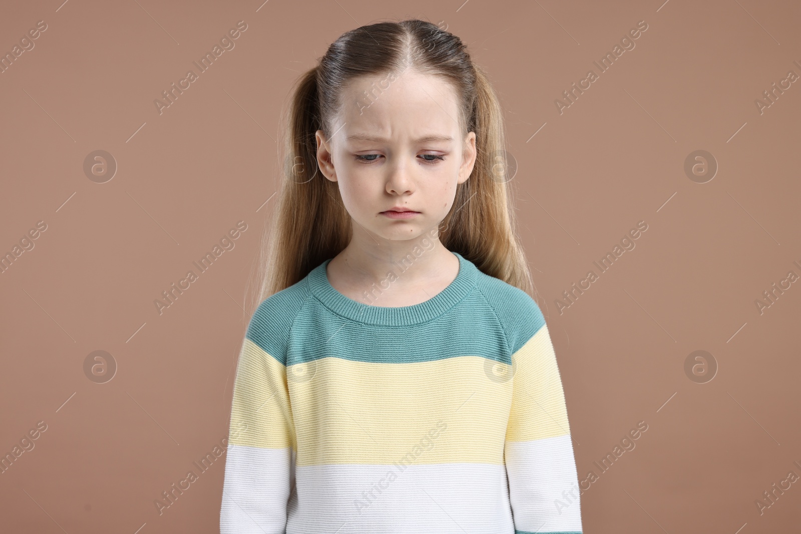 Photo of Portrait of sad girl on light brown background