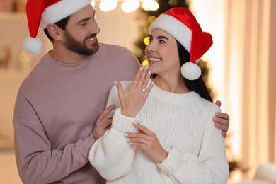 Making proposal. Happy woman with engagement ring and her fiance at home on Christmas