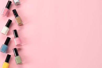 Photo of Pastel nail polishes in bottles on pink background, flat lay. Space for text