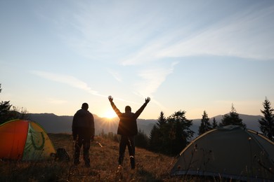 People in mountain camping at sunset, back view