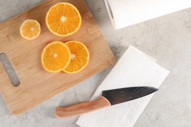 Photo of Paper towel, orange slices and knife on light table, flat lay