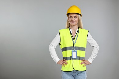 Photo of Engineer with hard hat and badge on grey background, space for text