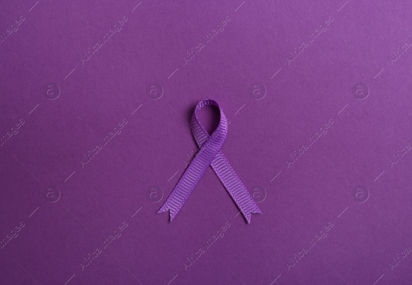 Photo of Purple awareness ribbon on color background, top view