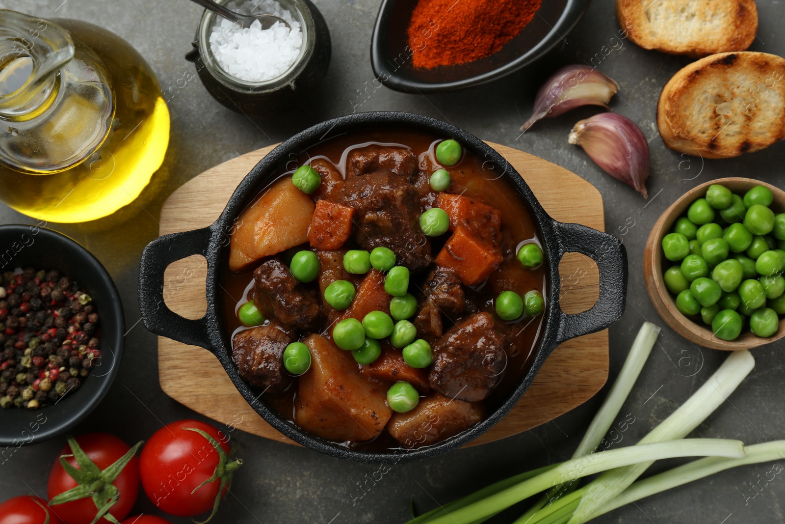 Photo of Delicious beef stew and ingredients on grey table, flat lay