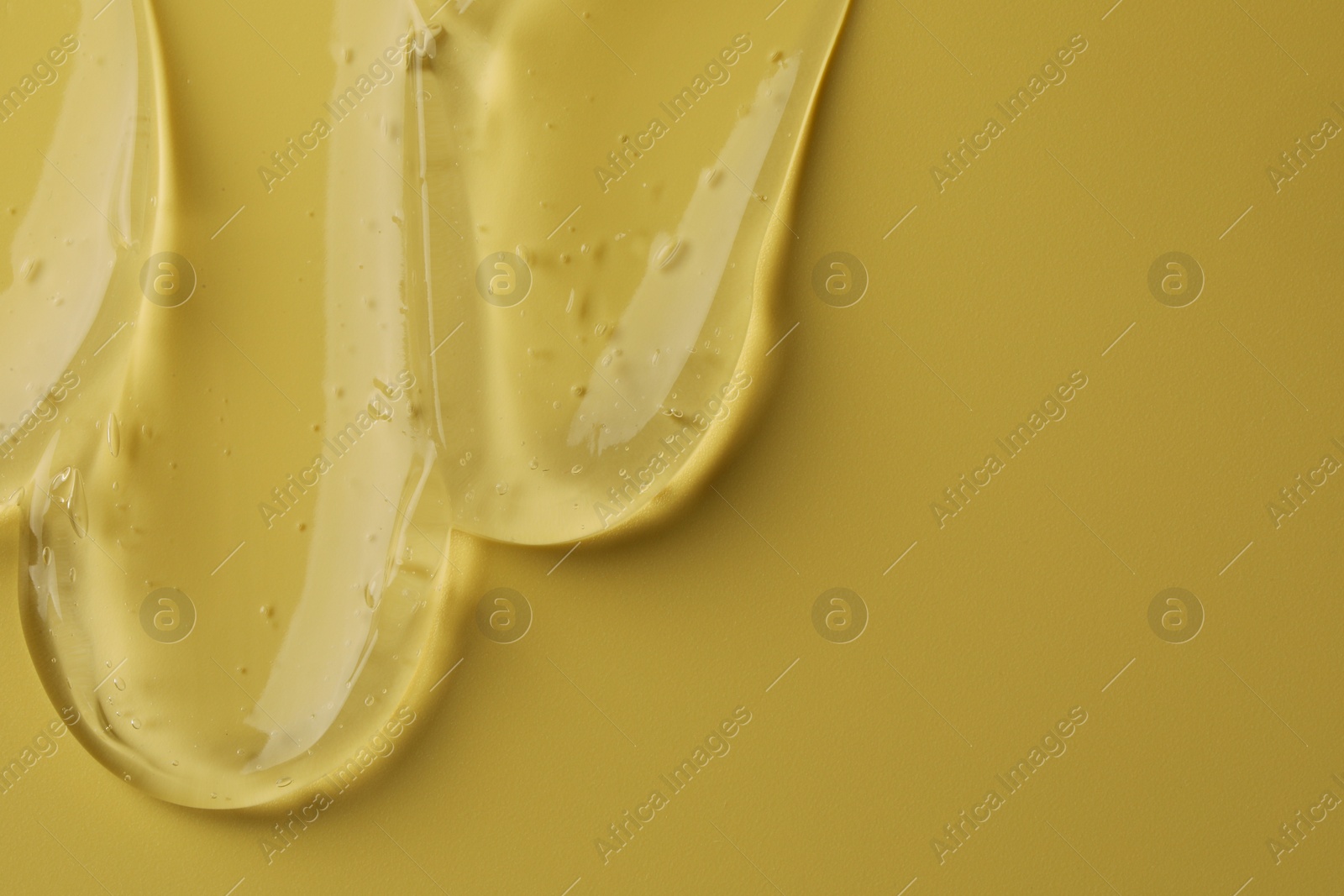Photo of Sample of clear cosmetic gel on yellow background, top view. Space for text