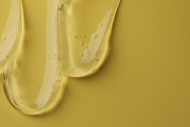 Photo of Sample of clear cosmetic gel on yellow background, top view. Space for text