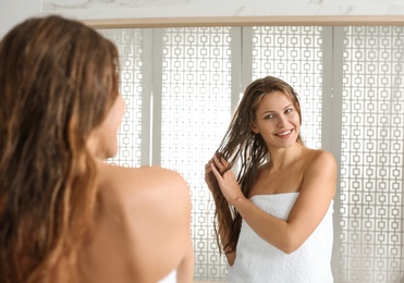 Image of Beautiful young woman with wet hair near mirror at home