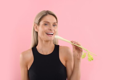 Photo of Woman with fresh celery stem on pink background