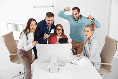 Group of office employees celebrating victory at workplace