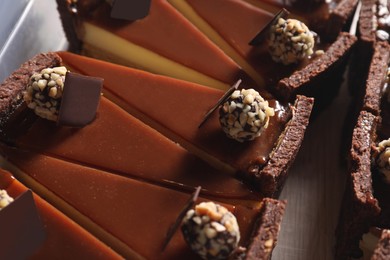 Photo of Pieces of delicious cheesecake with caramel and chocolate candies on table, above view