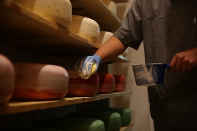 Photo of Worker coating cheese with wax in factory warehouse, closeup